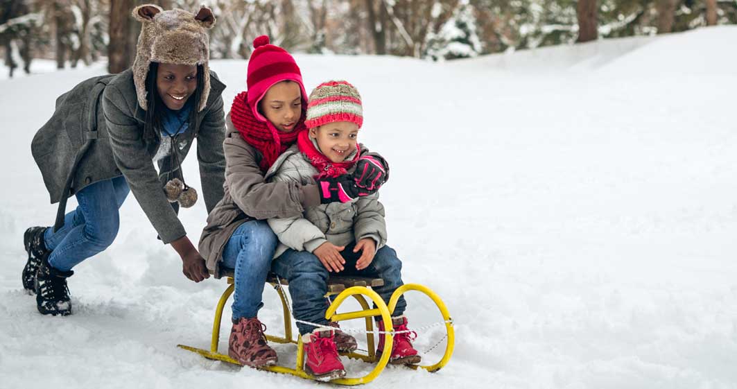 A family of three sledding on snow.